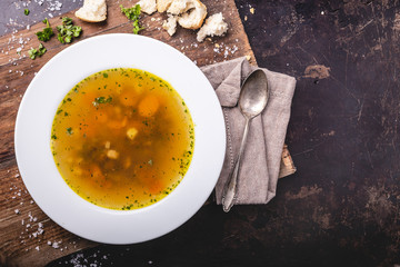 Beef soup with carrots and herbs on a dark background