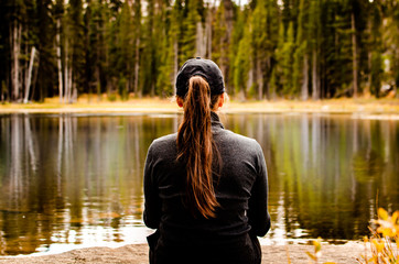 Woman wearing a hat sitting at Siesta Lake, Yosemite National Park, California