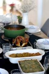 Table set for lunch with family or fiends. Minestrone soup, roast chicken,baked potatoes and spinach flan on the menu. Top view.