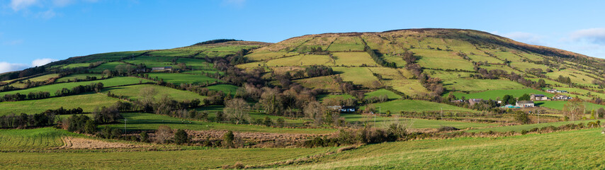 Fototapeta na wymiar Beautiful landscape panorama of fields, farms, and hills in the Irish countryside - Glenariff, County Antrim, Northern Ireland
