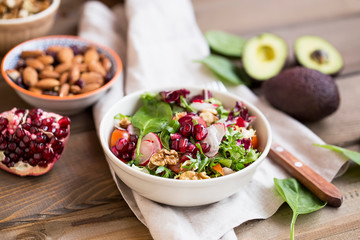 Fresh salad with spinach, arugula, radish, tomatoes, organic nuts and pomegranate