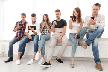 young people in casual clothes using gadgets