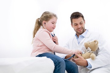 Girl playing with teddy bear and stethoscope