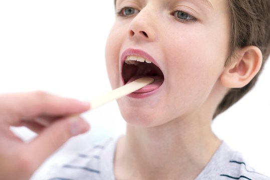 Boy with mouth open and tongue depressor