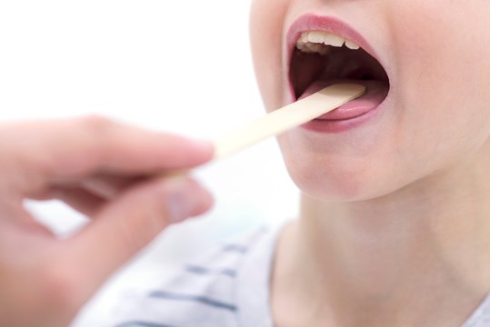 Boy with mouth open and tongue depressor