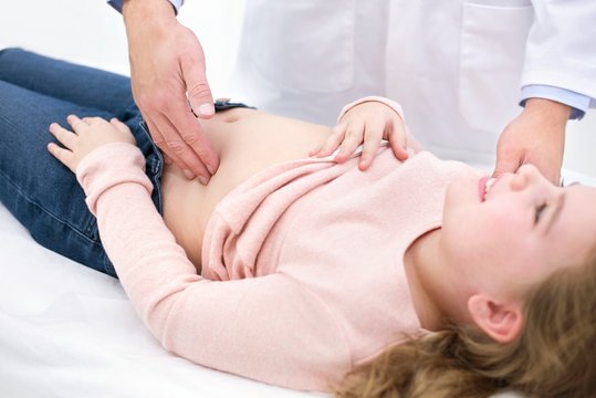 Doctor examining girl's abdomen