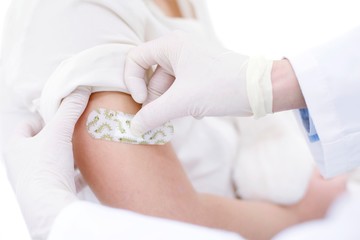 Doctor sticking plaster on girl's arm after injection