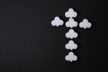 Cross gravestone symbol made of refined sugar on black background. Abstract gloomy symbolism with place for text.