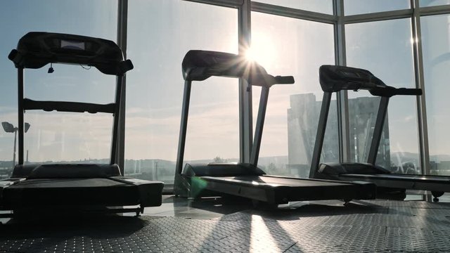 View of tread mill in sport gym near big window.