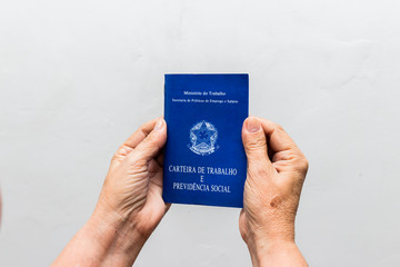 hands of Caucasian senior woman holding work book, Brazilian social security document