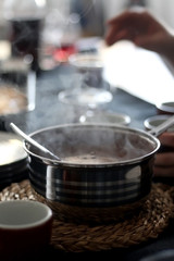 Pouring homemade hot black coffe from large metal pot. Selective focus.