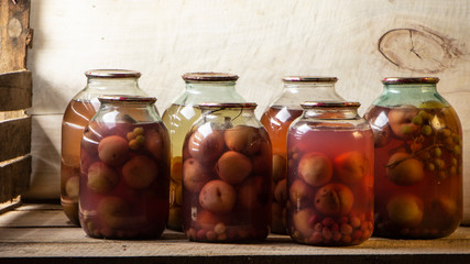 Several cans of compote on a wooden shelf in a dark basement