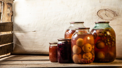 Several cans of compote on a wooden shelf in a dark basement