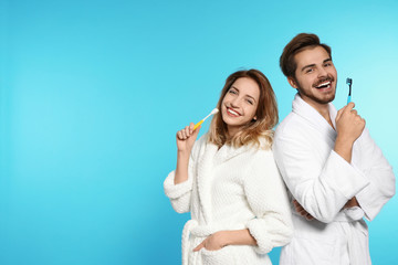 Portrait of young couple with toothbrushes on color background. Space for text - obrazy, fototapety, plakaty