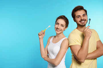 Portrait of young couple with toothbrushes on color background. Space for text