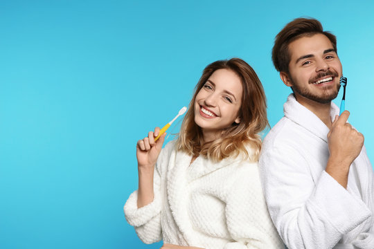 Portrait of young couple with toothbrushes on color background. Space for text