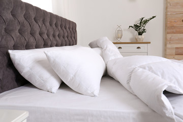 Fototapeta na wymiar Large comfortable bed in light room. Stylish interior