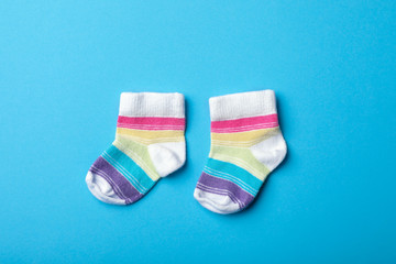 Pair of cute child socks on color background, top view