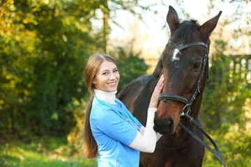 Obraz premium Veterinarian in uniform with beautiful brown horse outdoors. Space for text