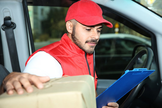 Young courier checking amount of parcels in delivery van