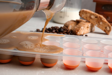 Pouring coffee drink into ice cube tray on table, closeup