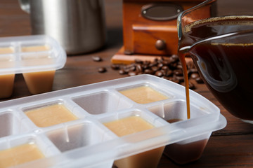 Fototapeta na wymiar Pouring coffee in ice cube tray on table, closeup