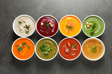 Various cream soups in bowls on grey background, top view