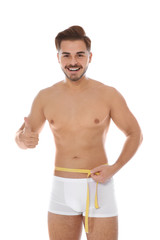 Fit man measuring his waist on white background. Weight loss