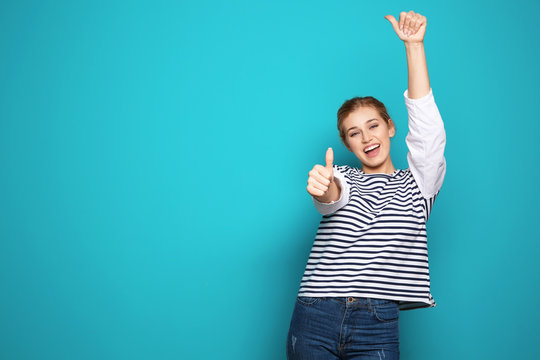 Happy young woman showing thumbs up on color background, space for text. Celebrating victory