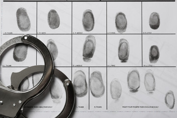 Police handcuffs and criminal fingerprints card, closeup
