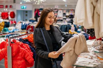 Customer young woman choosing baby clothes or children's wear in the shop. Buying in the store for infant kids