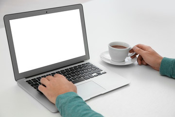 Fototapeta premium Young man working with modern laptop at table, closeup. Mockup for design