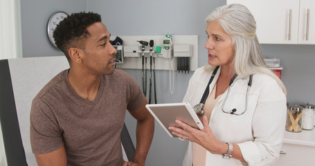 Portrait of young black man consulting with mature female doctor indoors medical clinic. Close up...