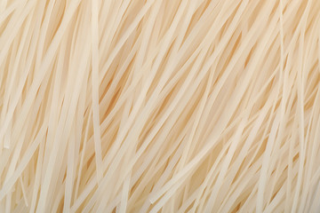 Raw rice noodles as background, closeup. Delicious pasta