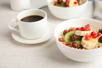 Quinoa porridge with hazelnuts, kiwi, banana and pomegranate seeds served for breakfast on white wooden table
