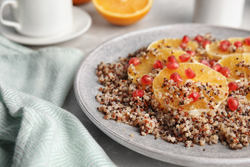 Plate of quinoa porridge with orange and pomegranate seeds on table, closeup