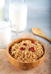 Rolled oats or oat flakes in bowl with wooden spoons and bottle of milk on background.