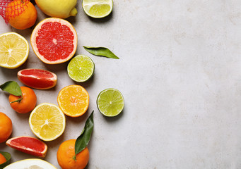 Different citrus fruits on grey background, top view. Space for text