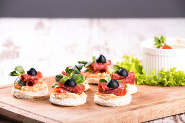 Canapes with salami on a wooden background