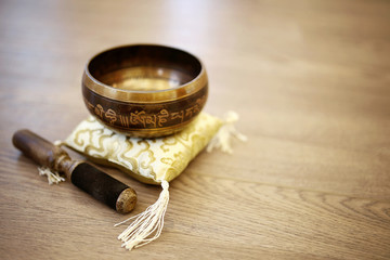Tibetan Singing Bowl on Silk Yellow Pillow Cushion and Wood Background