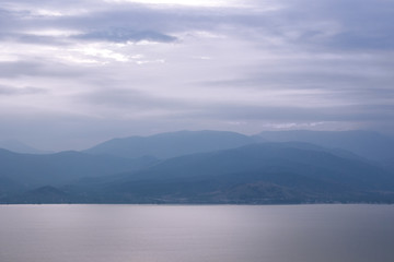 abstract mystic foggy mountains silhouette near big lake calm water surface background wallpaper pattern scenery landscape