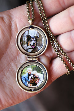 Woman's Hand Holding Antique Locket with Photos of Children and Pet Dog Inside