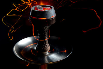 Shisha bowl with craft tobacco and red coil with hookah smoke background.