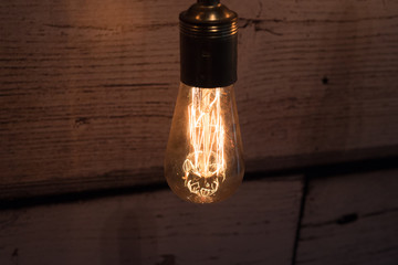 close-up of old lit bulb, worn wooden background