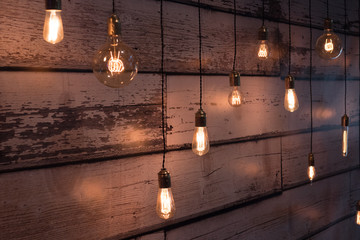 close-up of old lit bulb, worn wooden background