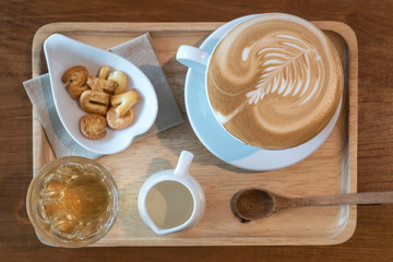 Coffee time in morning set hot latte art with milk tea and cracker in wooden tray on wood table, top view