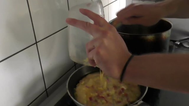 Professional Greek cook pouring egg mixture into frying pan and cooking,  close up of hands; cooked and ready to eat omelette or omelet in the plate on the table, handheld camera