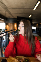 Smiling woman eating fresh salad in cafe