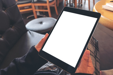 Mockup image of a woman holding black tablet pc with blank white screen while sitting in cafe