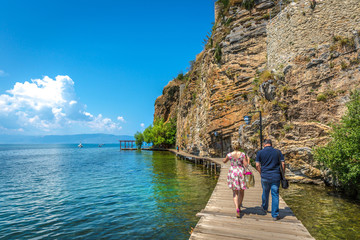 Ohrid, Macedonia - June 1st 2018 - Couple walking in a narrow wood path in front of a steep cliff...